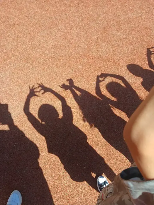 Sombras de niños de Fun Day haciendo figuras con las manos sobre el piso de un patio