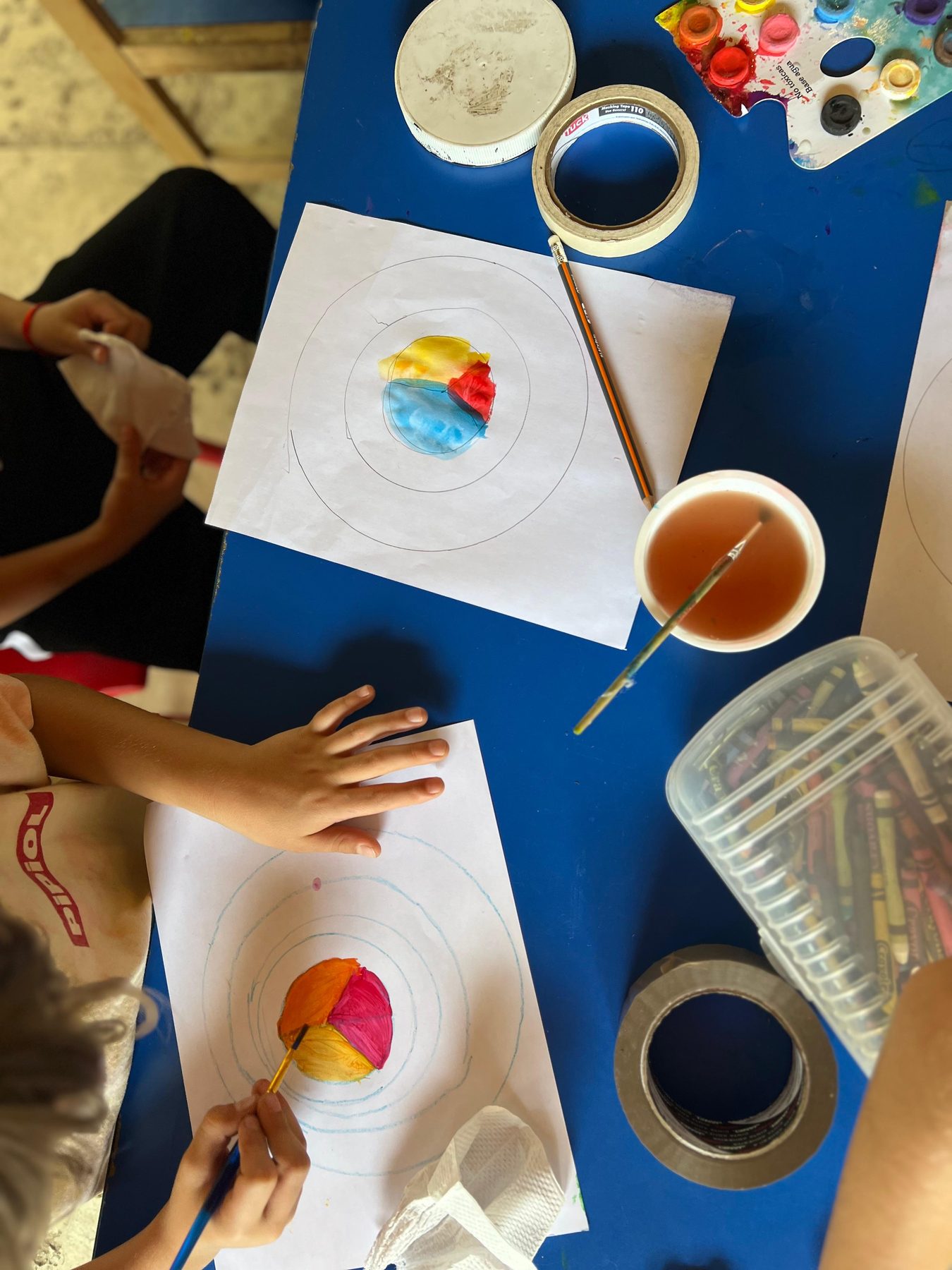 Manos de niños pintando con acuarelas, vistas desde arriba, en un Fun Day de Tribu